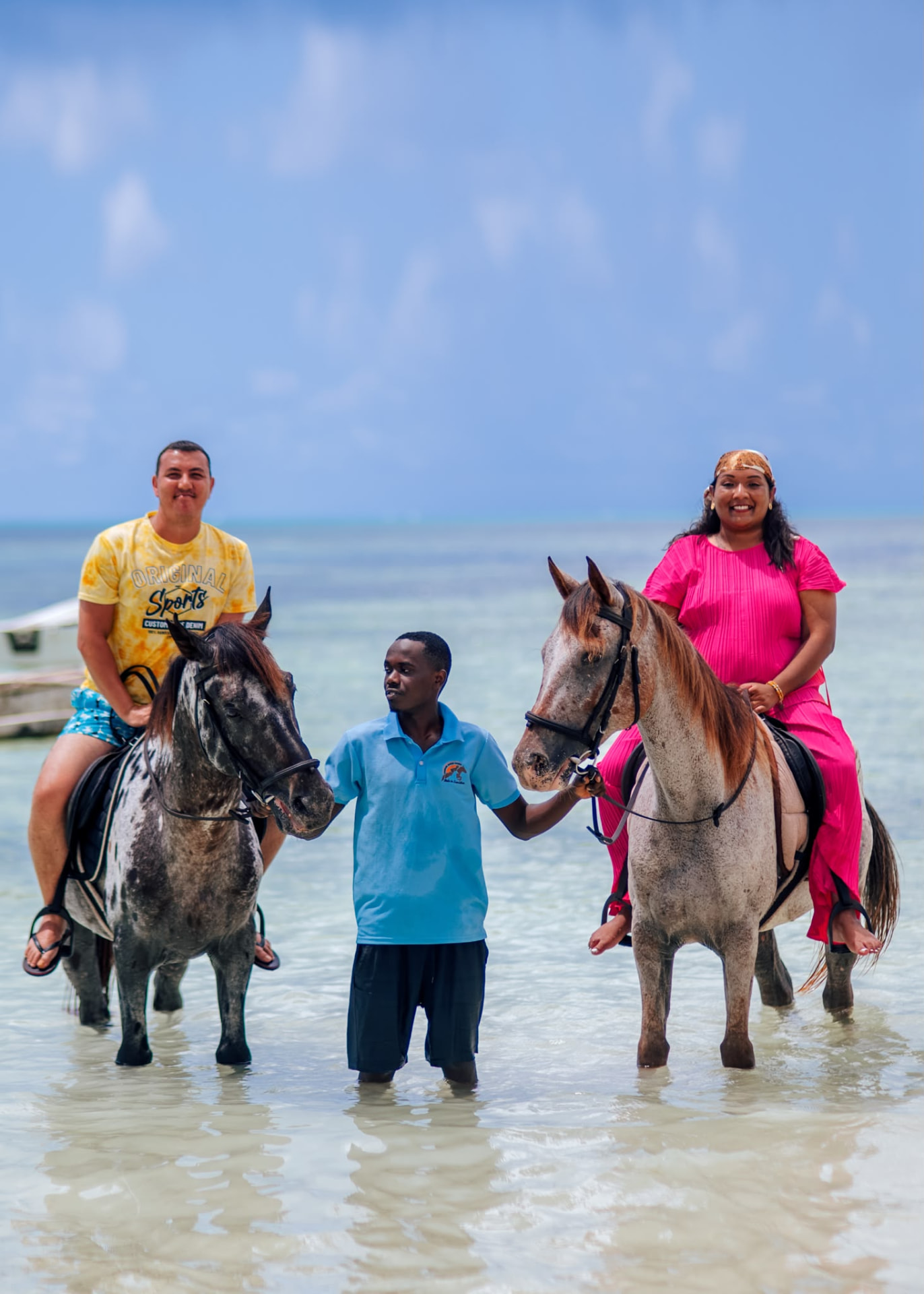 Beach horse riding in Paje, Zanzibar — two guests riding spotted horses through the shallow lagoon with their guide