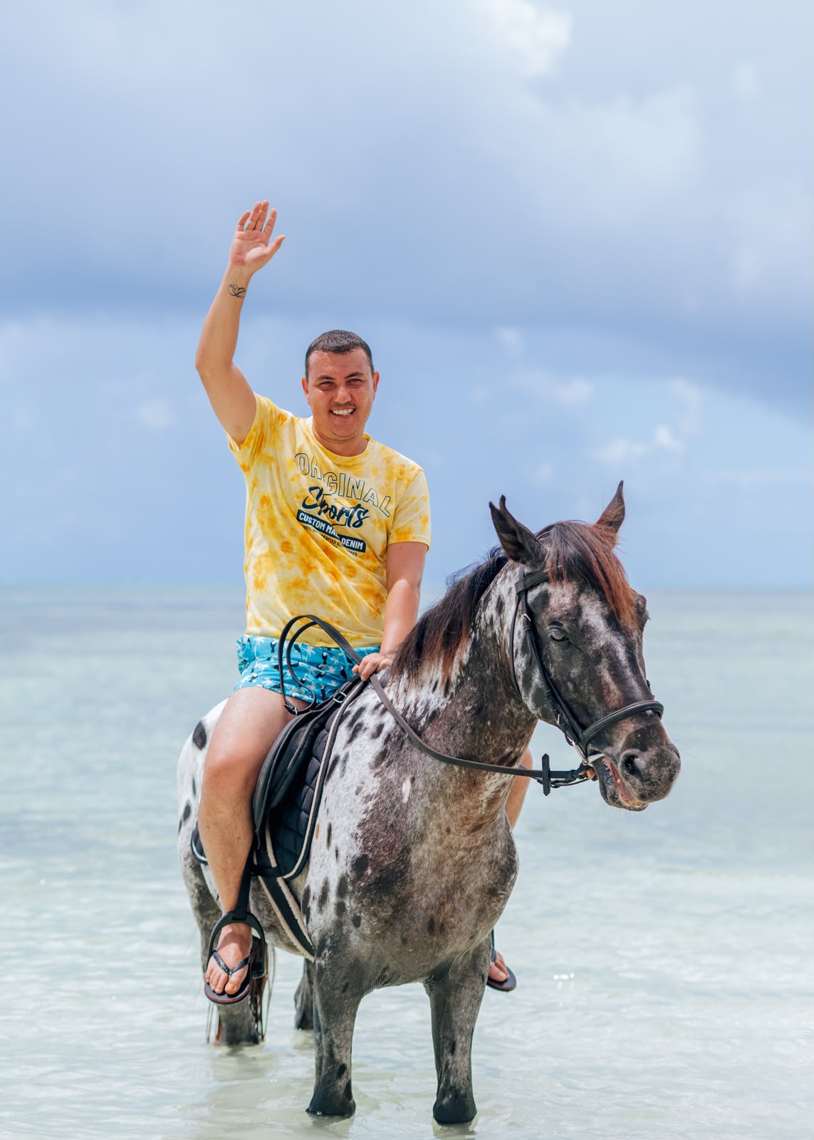 Beach horse riding in Paje, Zanzibar — rider waving from horseback in the lagoon