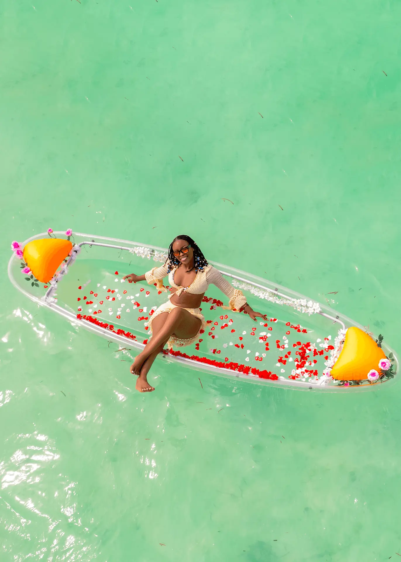Transparent kayak photoshoot in Paje, Zanzibar — guest floating in a clear kayak filled with red rose petals